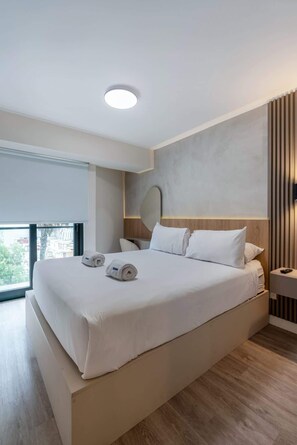 Une chambre d’hôtel moderne avec un grand lit, une table de chevet, une commode et une vue sur la ville.