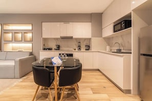 Una cocina moderna con armarios blancos, un microondas integrado y una cafetera.