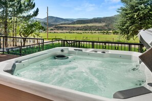A hot tub with a view of a green landscape and mountains in the background. - 1900's Farmhouse (New Castle)
