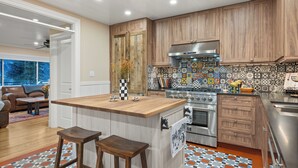 A modern kitchen with wooden cabinets, a central island, and a colorful backsplash. - 1900's Farmhouse (New Castle)
