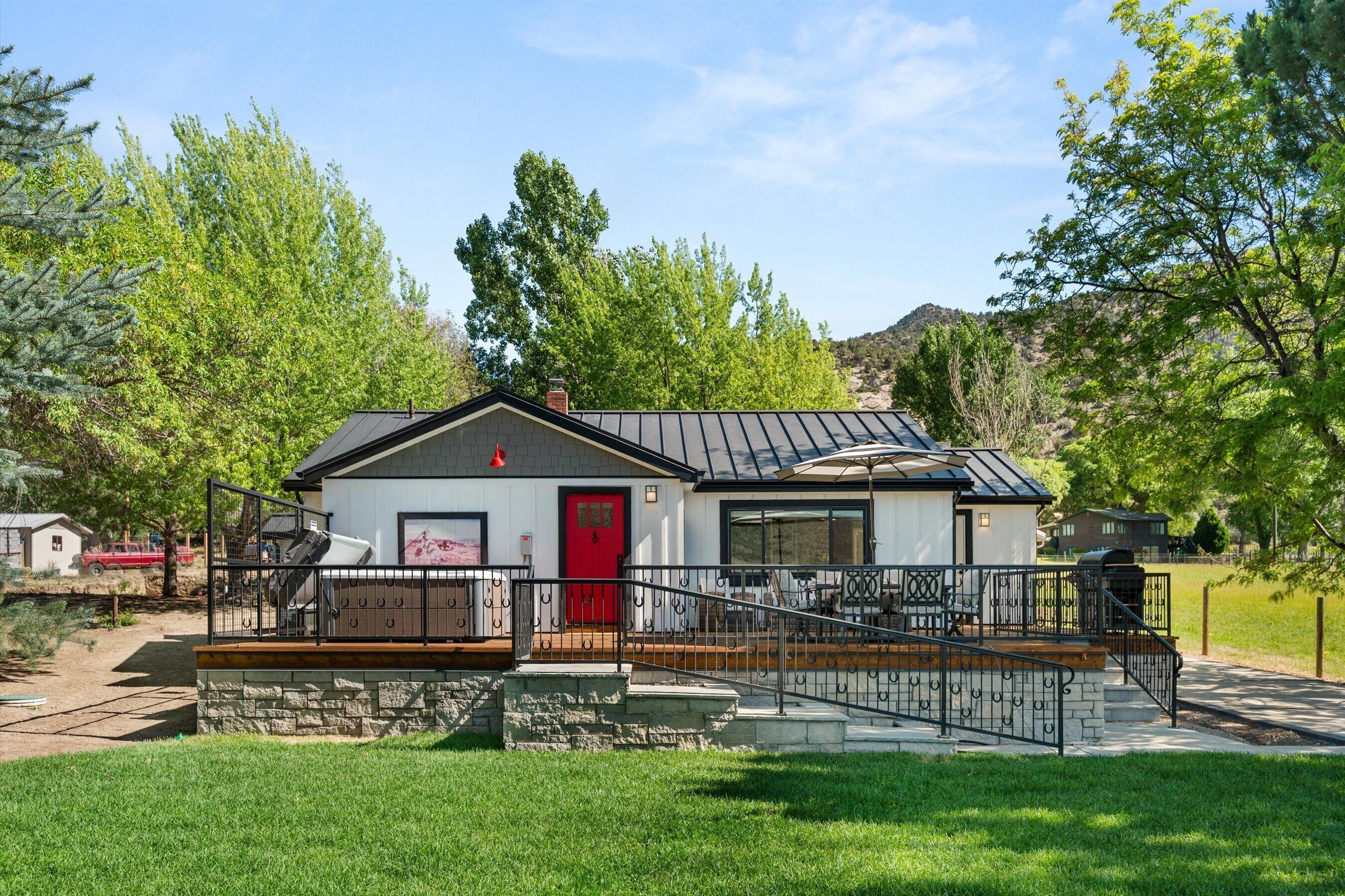 A single-story house with a red door, a covered porch, and a stone foundation.