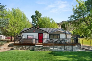 A single-story house with a red door, a covered porch, and a stone foundation. - 1900's Farmhouse (New Castle)