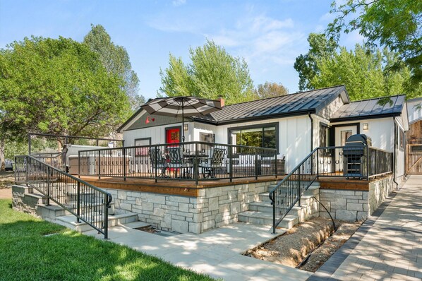 A modern house with a stone deck, outdoor seating, and a red door. - 1900's Farmhouse (New Castle)