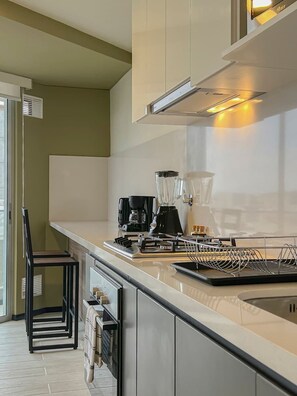 A modern kitchen with a built-in coffee maker, a kettle, and a kettle rack.