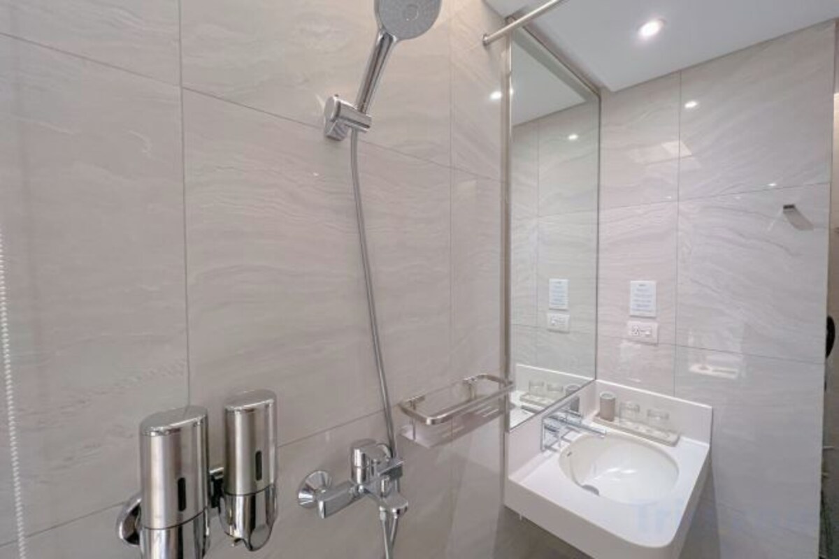 A modern bathroom with a glass shower enclosure, a wall-mounted sink, and a large mirror.