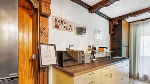Une cuisine avec un plan de travail en bois, une machine à café et une enseigne indiquant « Kaffee-Bar ».