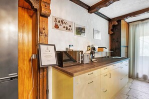 A kitchen with a wooden countertop, a coffee machine, and a sign that reads 'Kaffee-Bar'.