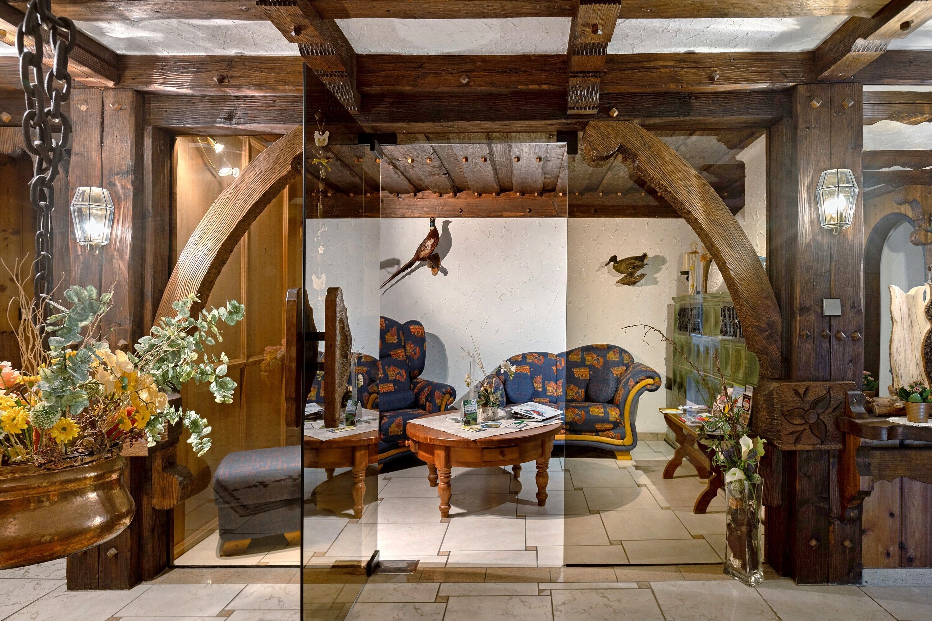 A rustic interior with wooden beams, a sofa set, a coffee table, and decorative plants.