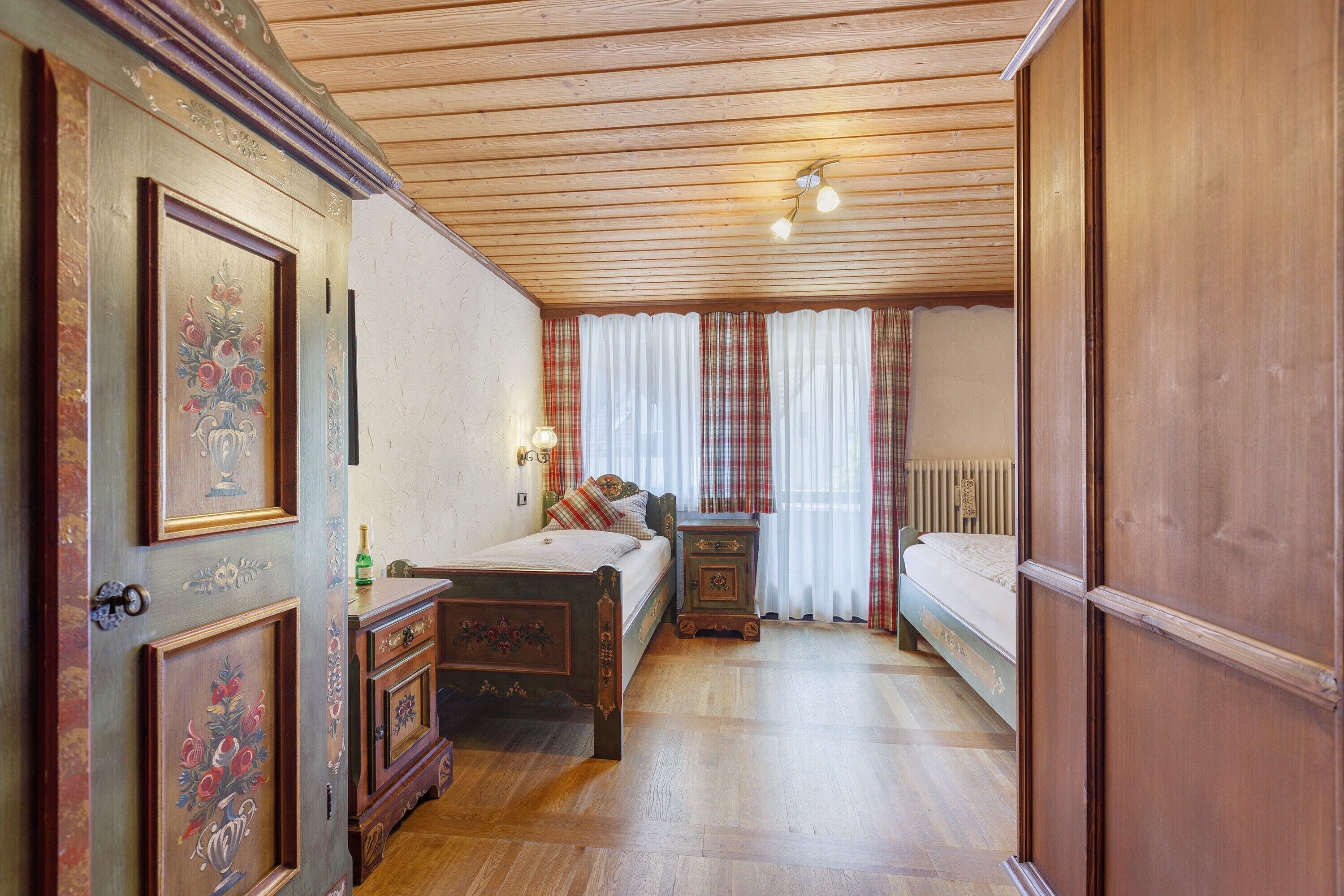 A traditional room with a wooden ceiling, a bed, a bedside table, and a wardrobe.