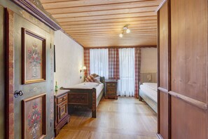 A traditional room with a wooden ceiling, a bed, a bedside table, and a wardrobe.