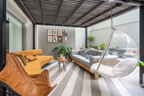 A modern outdoor living area with a sofa, a hanging chair, and a coffee table. - Geko | Stylish Loft w/AC near Malecón de Barranco (Barranco)