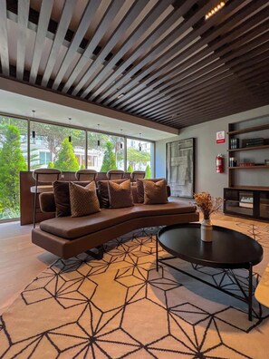 A modern lounge area with a curved sofa, a round coffee table, and a geometric patterned rug. - Geko l Contemporary 1BR in Barranco w/ balcony (Lima)