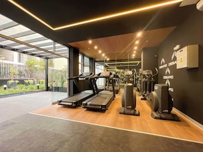Une salle de sport moderne équipée de tapis de course, de vélos elliptiques et de matériel de musculation.