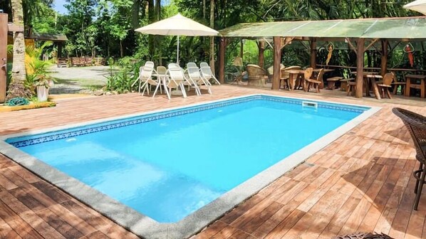 Ein rechteckiger Pool mit Fliesenrand, umgeben von einer Holzterrasse.