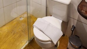 Een badkamer met een wit toilet, een houten vloer en een douchecabine van glas.