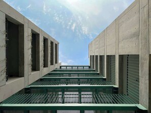 Ein modernes Gebäude mit einer Reihe aus Betonsäulen und grünen Metallgeländern.