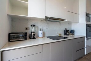 A modern kitchen with a built-in toaster, a blender, a coffee maker, and a stove. - Geko | Panoramic 2BR w/ Ocean view in Barranco (Barranco)