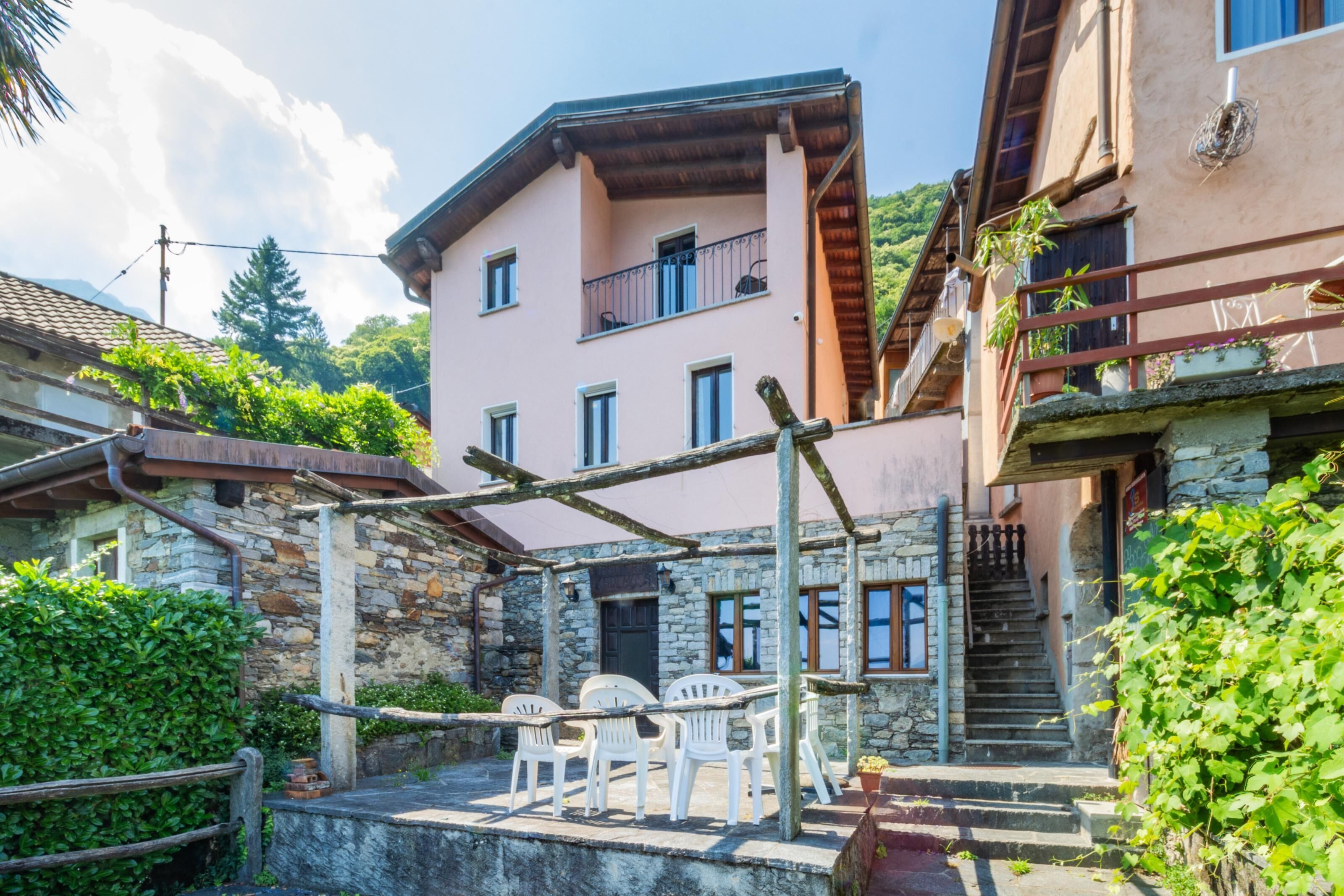 A stone building with a balcony, outdoor seating, and a staircase.