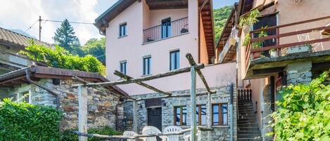 A stone building with a balcony, outdoor seating, and a staircase.