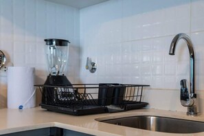A kitchen with a blender, a sink, and a faucet.