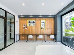 A modern office space with a glass partition, wooden panel wall, and a long table with chairs.