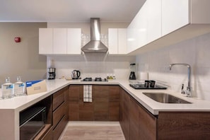 A modern kitchen with white cabinets, a stainless steel range hood, a built-in oven, and a sink.