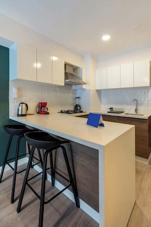 Una cocina moderna con una isla central, taburetes de bar, cafetera y una estufa integrada.