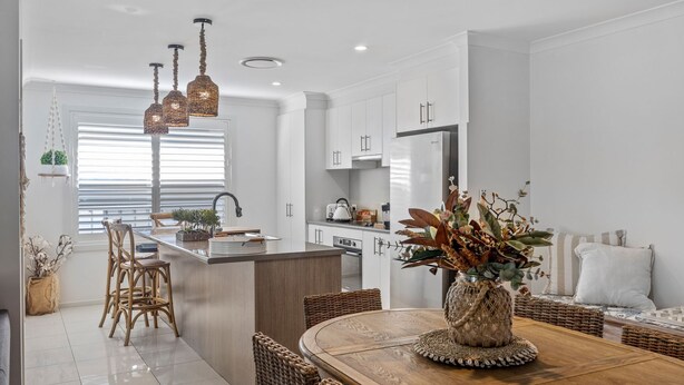 Une cuisine moderne avec des meubles blancs, un îlot central et des luminaires suspendus.