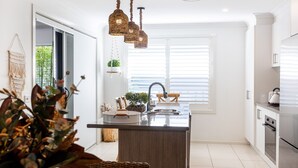 Une cuisine moderne dotée d’un îlot central, de meubles blancs et d’un luminaire suspendu.