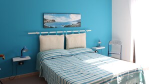 Une chambre à coucher avec un lit, une table de chevet, une chaise et un tableau au mur.