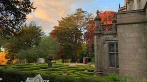 Un jardin à la française, avec des haies taillées avec soin, un bâtiment de style classique et un banc.
