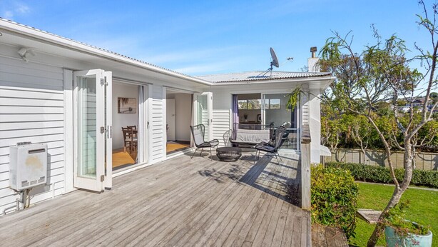 A single-story house with a covered patio area, a sliding glass door leading to an interior room, and a satellite dish on the roof. - Cosy Retreat in Rothesay Bay| by Furnished Rentals (Auckland)