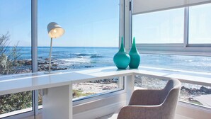 Une chambre moderne dotée d’une grande fenêtre donnant sur une côte rocheuse.