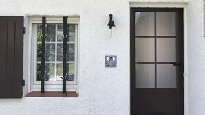 A white building with a black door, a window with a number plate, and an air conditioning unit mounted on the wall. - Mazet en camargue in a secure, comfortable residence 8 minutes from les saintes (Saintes-Maries-de-la-Mer)