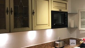 A kitchen with green cabinets, a microwave, a toaster, and a kitchen storage box. - Mazet en camargue in a secure, comfortable residence 8 minutes from les saintes (Saintes-Maries-de-la-Mer)