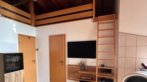 A room with wooden flooring, a wooden desk with a TV, a small stool, and a fireplace. - *Lake House* – an idyllic vacation home right on the lake with a terrace and a fireplace (Lauenförde)