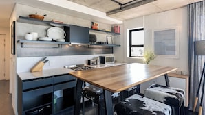 Una cucina moderna con un tavolo in legno, sgabelli bianchi e neri e scaffali integrati con stoviglie.