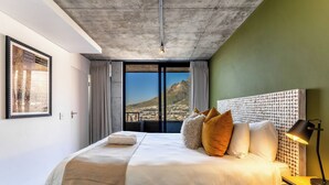 Una moderna camera d'albergo con un ampio letto, vista su una montagna e un soffitto in cemento.