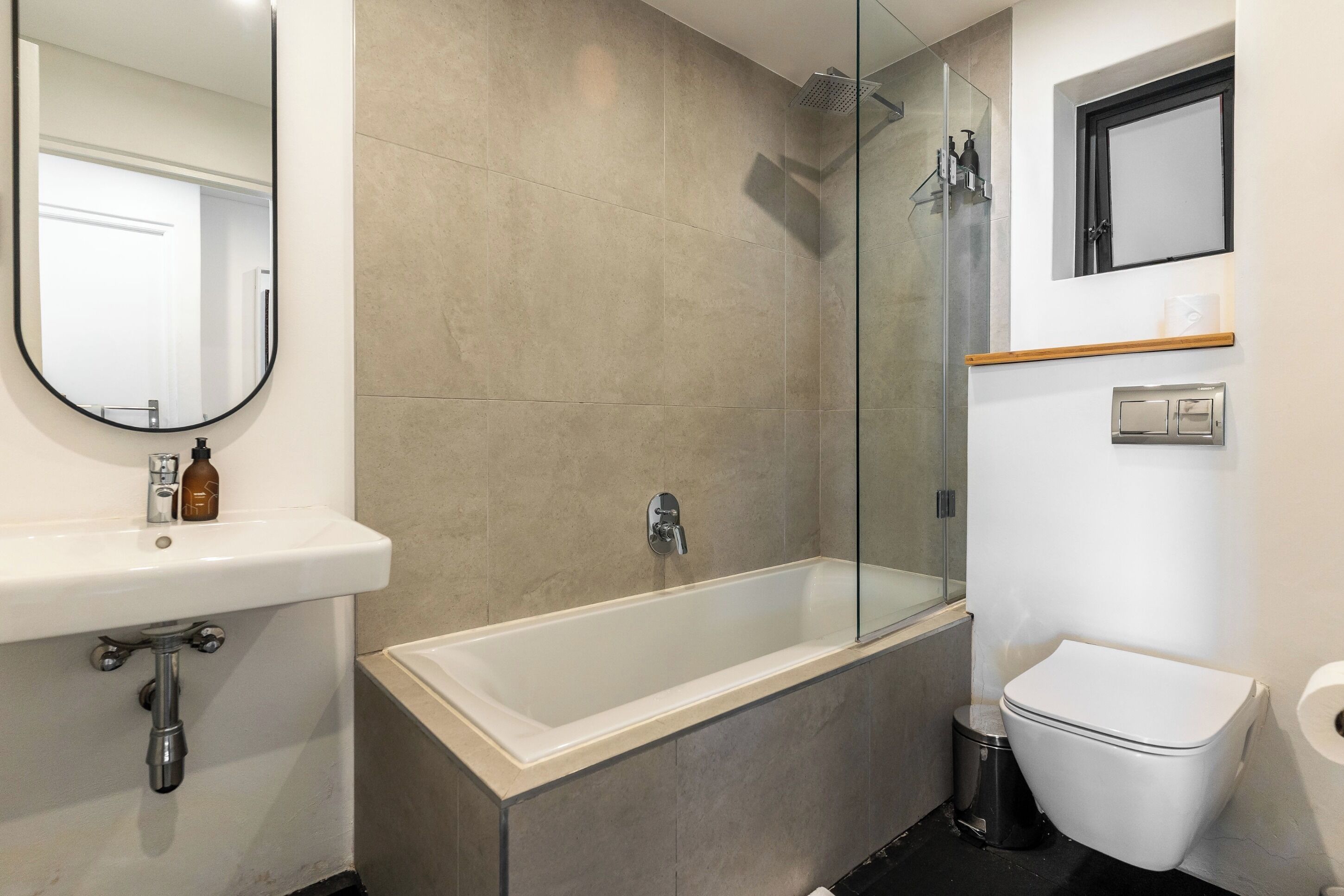 A modern bathroom with a bathtub, a toilet, a sink, and a glass shower enclosure.