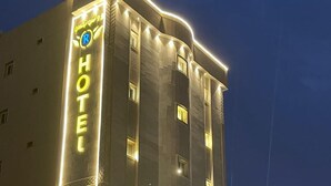 Un hôtel dont la façade est ornée d’une grande enseigne « HÔTEL », doté de nombreuses fenêtres et d’une entrée bien éclairée.