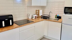 A modern kitchen with white cabinets, a black countertop, a built-in stove, a sink, and a refrigerator.