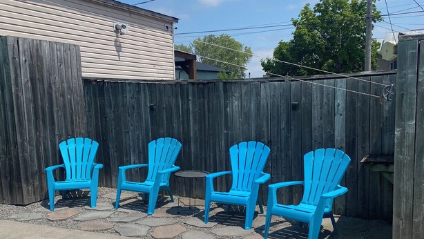 A backyard with a swimming pool, a wooden fence, and blue chairs. - Spacious Century 3-bed in Downtown Wellington with in Ground Pool and parking! (Prince Edward)