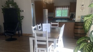 A dining area with a wooden table and chairs, a chandelier, and a welcome sign. - Spacious Century 3-bed in Downtown Wellington with in Ground Pool and parking! (Prince Edward)