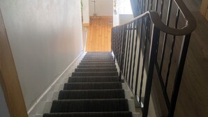 A staircase with a black railing, white walls, and a wooden floor. - Spacious Century 3-bed in Downtown Wellington with in Ground Pool and parking! (Prince Edward)
