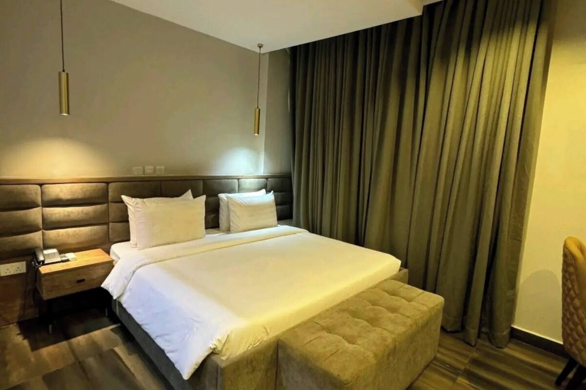 Una habitación de hotel moderna con una cama grande, mesitas de noche, un escritorio y una silla.