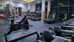 Ett gym med olika typer av träningsutrustning, stora fönster och en modern takdesign.