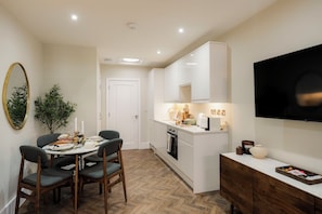 A compact kitchen with white cabinets, a built-in oven, and a dining area with a round table and four chairs.