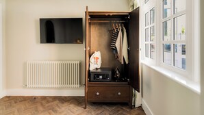 A room with a wooden wardrobe, a radiator, and a window with multiple panes. - Clifton Road Apartments | No.1 (Bristol)