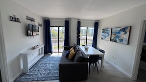 Een moderne woonkamer met een bank, een eettafel en kunstwerken.