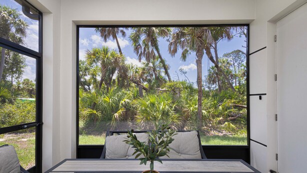 A room with a large window overlooking a lush garden with palm trees and other greenery.